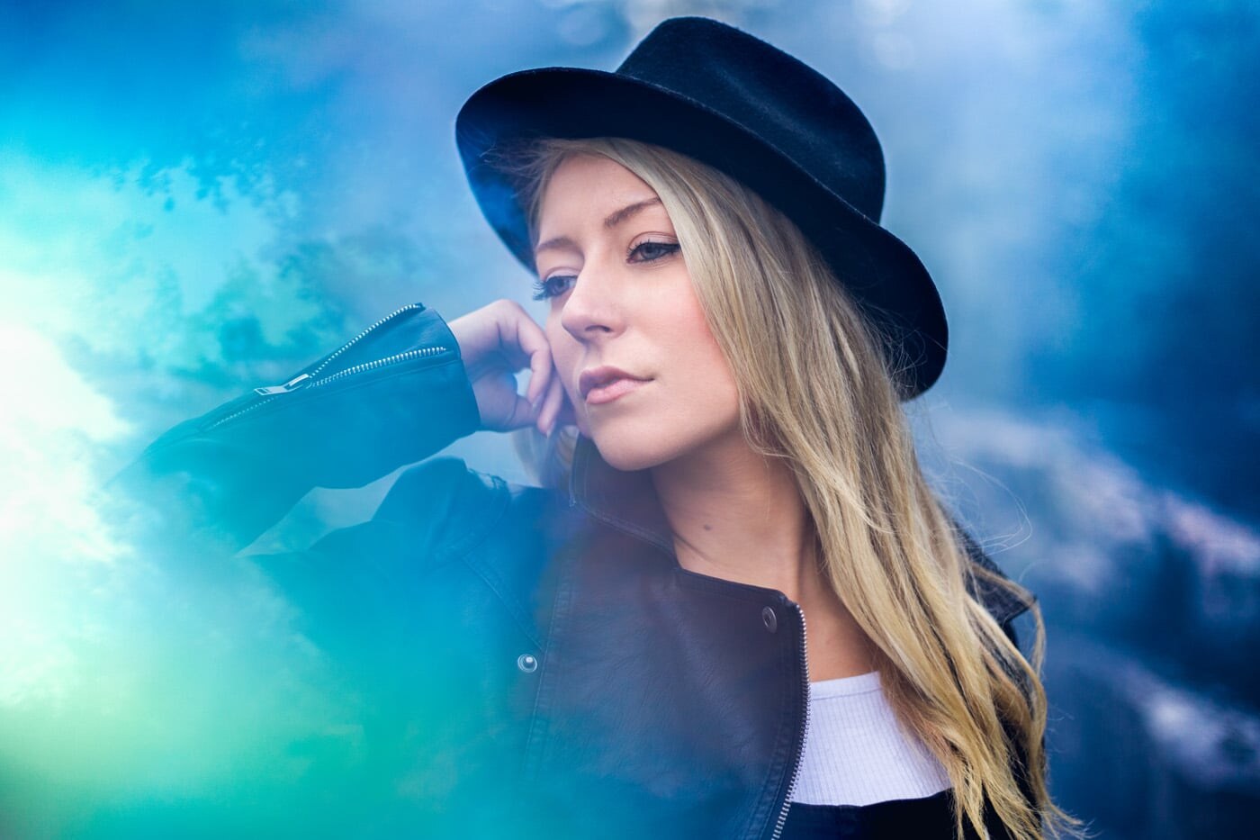 photo portrait studio sur lyon avec tommy loska, portrait d'une femme blonde avec un chapeau noir sur fond bleu