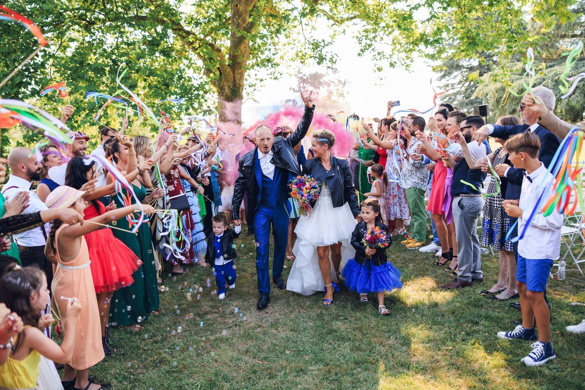 Sortie des mariés sous les acclamations colorées des invités avec confettis et rubans